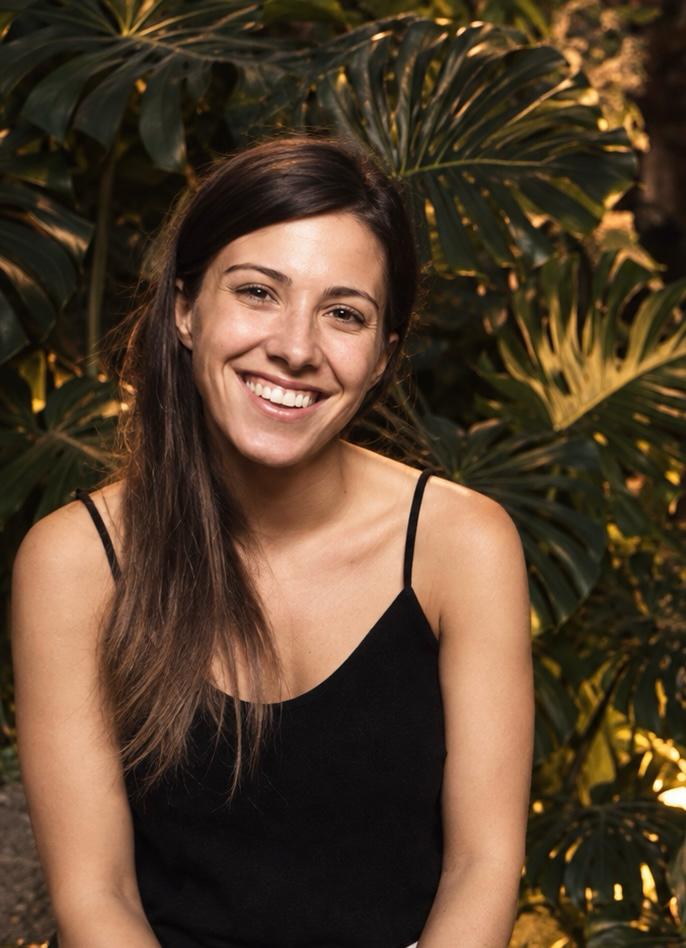 Ana, sonriendo frente a un fondo de vegetación
